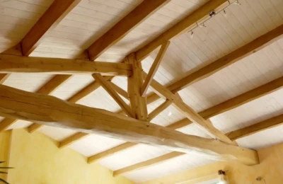 Une charpente traditionnelle en bois massif avec rampe de luminaires Charpente intérieure en bois massif avec luminaires