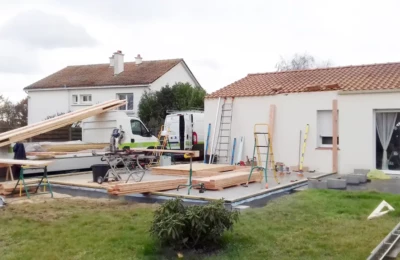 Ajout d'une extension : phase de préparation, dépose du matériel Des planches de bois posées sur une dalle