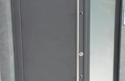 Porte d'entrée grise avec une barre de tirage Une porte d'entrée de couleur grise avec poignée verticale