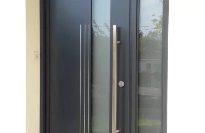 Porte d'entrée noire avec une barre de tirage et un bandeau décoratif dorés Une porte d'entrée de couleur noire décorée