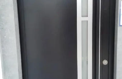 Porte d'entrée noire avec une barre de tirage et un bandeau décoratif Une porte d'entrée de couleur noire avec un bandeau métallisé vertical